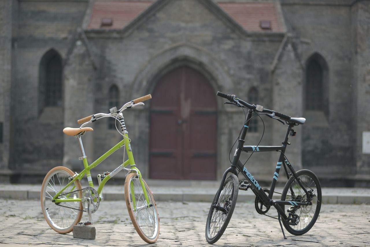 Servicios Two modern bicycles parked on cobblestone street in front of historic building.