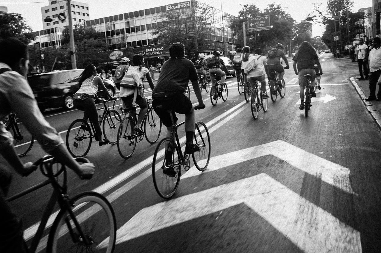 Sobre Nosotros A group of cyclists ride down a city street, showcasing urban biking culture.